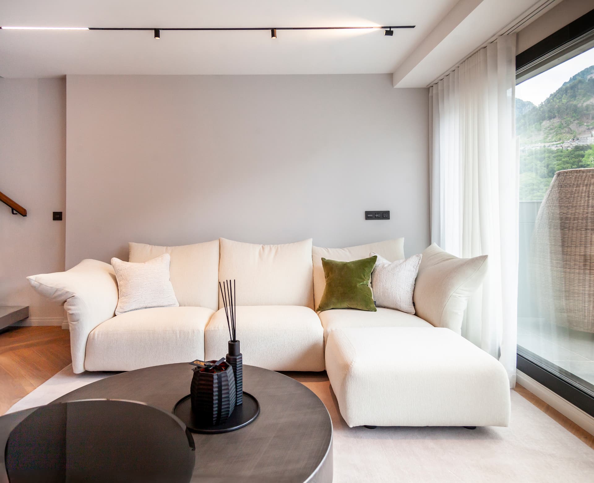 Sofà blanc modular amb coixins verds davant la terrassa